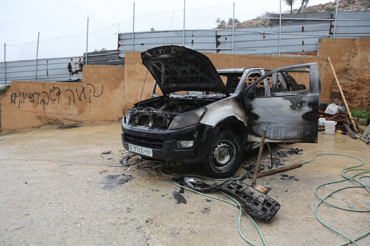 فلسطينيون يقفون في موقع حريق سيارة أشعله مستوطنون إسرائيليون في بلدة حوارة، جنوب نابلس في الضفة الغربية، 28 ديسمبر/كانون الأول 2025. صورة: محمد ناصر