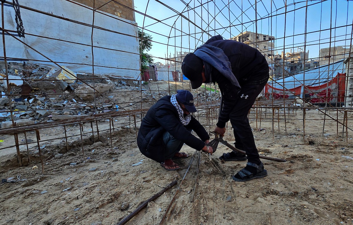 الفلسطيني هشام أبو عية يبني مأوى مؤقت لعائلته المكونة من ثمانية أفراد باستخدام قضبان حديدية استخرجها من أنقاض منزله الذي دُمر في هجمات إسرائيلية بمنطقة بطن السمين في خان يونس،  19 ديسمبر/كانون الأول 2025. تصوير: طارق محمد/ (APA )