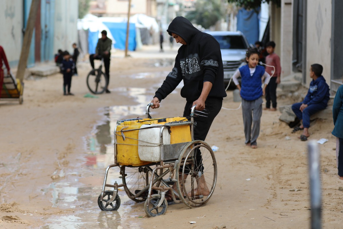 يتجمع الفلسطينيون لتلقي مياه الشرب مجانًا في مخيم البريج للاجئين، في ظل تفاقم أزمة نقص المياه وتدهور البنية التحتية، 21 ديسمبر/كانون الأول 2025. صورة: رمزي أبو عامر