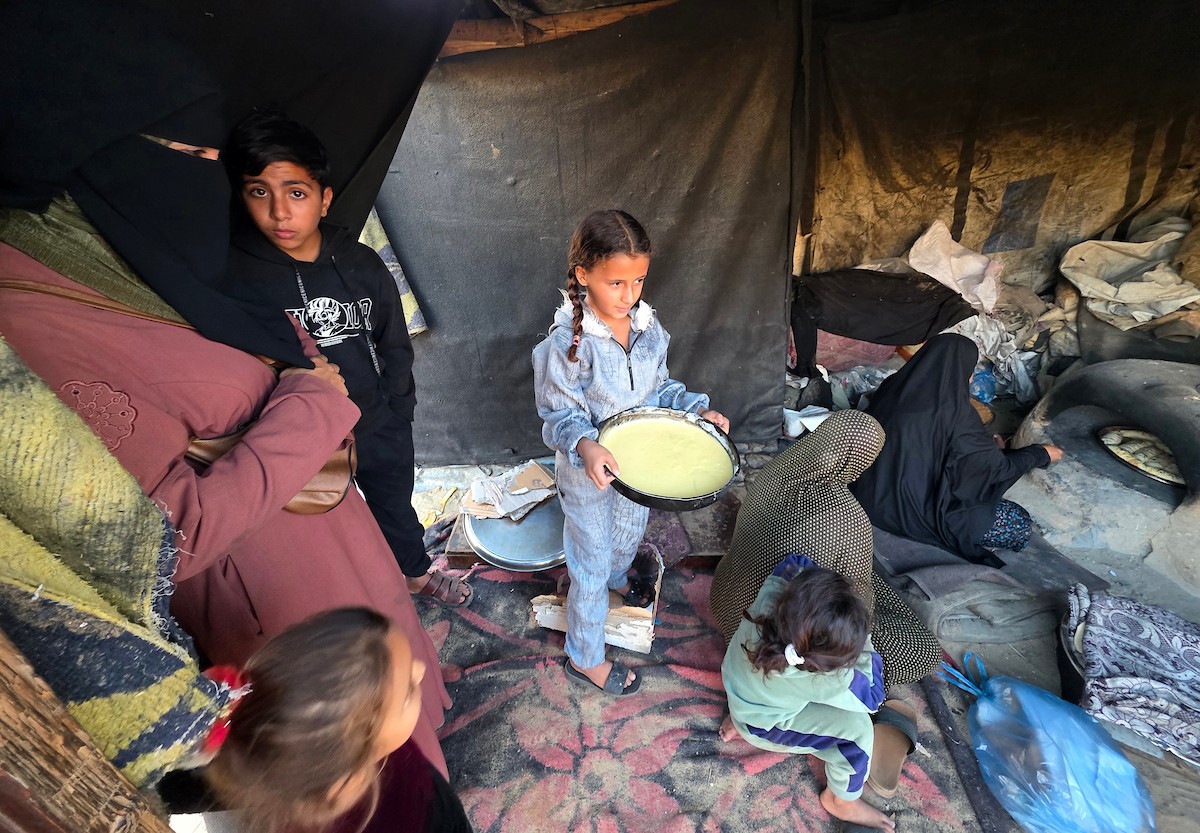 يتجمع فلسطينيون حول أفران طينية مؤقتة لطهي الطعام في قطاع غزة، بعد عشرة أسابيع من وقف إطلاق النار، في ظل شحّ غاز الطهي بسبب القيود الإسرائيلية على دخوله إلى القطاع