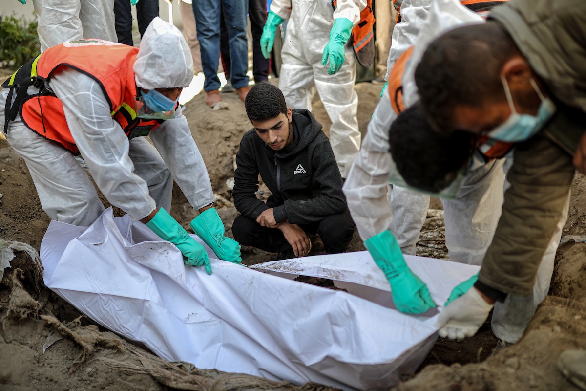 منقذون ومتطوعون فلسطينيون يستخرجون جثث ضحايا الحرب من مقبرة مؤقتة داخل المستشفى العربي المعمداني بمدينة غزة، ليعاد دفنها