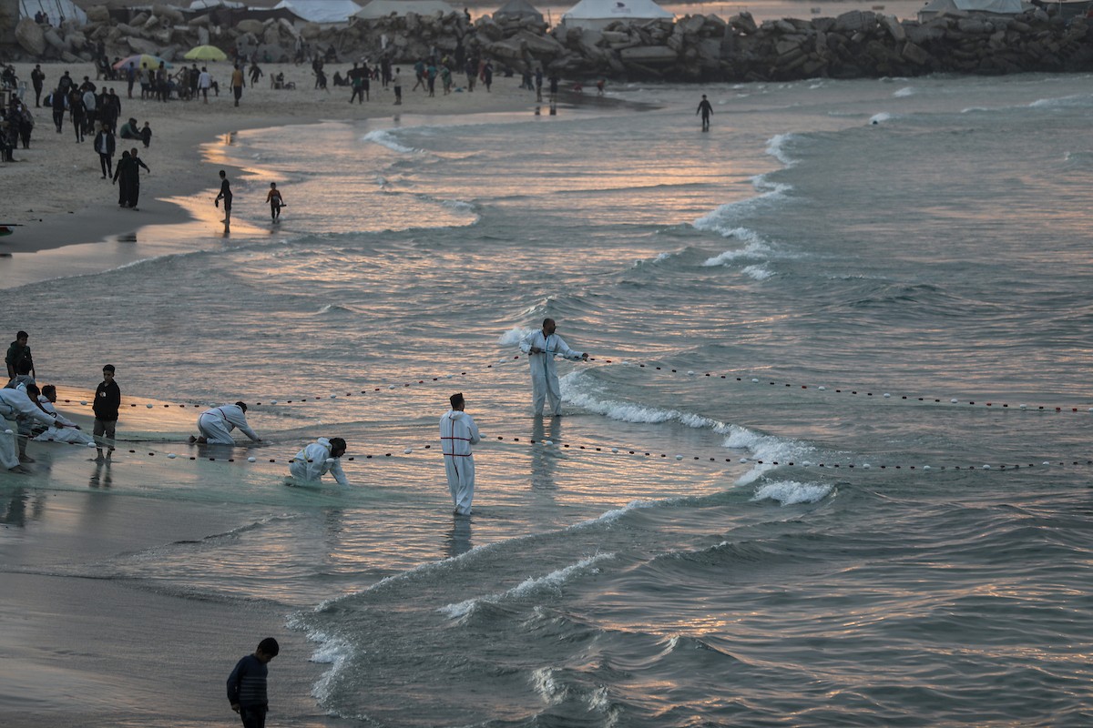يقضي فلسطينيون نازحون وقتًا على الشاطئ مقابل خيامهم الممتدة على طول ميناء غزة، في غزة، 5 ديسمبر/كانون الأول 2025. تصوير: عمر أشتوي