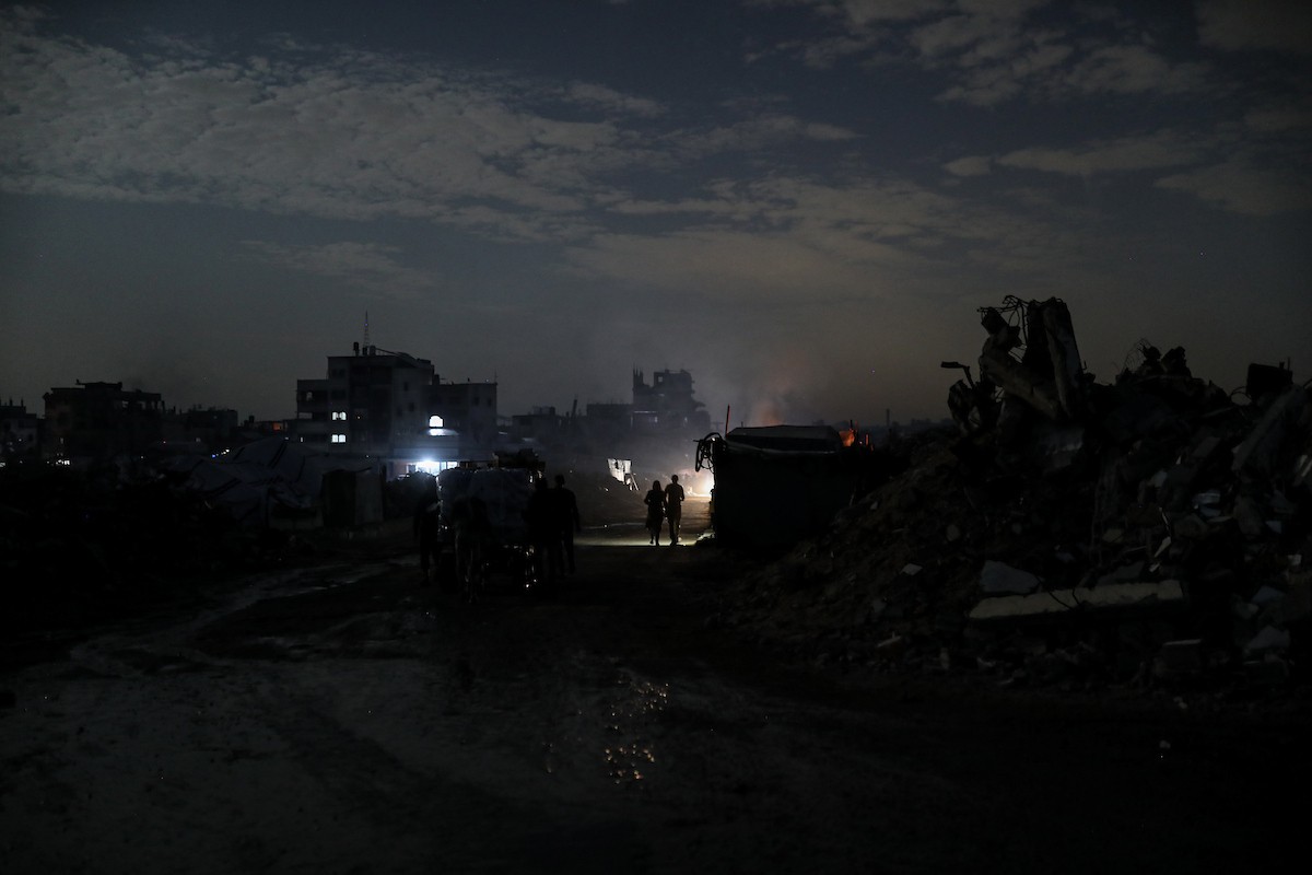 يعيش الفلسطينيون حياتهم اليومية ليلاً في خيام نصبت فوق أنقاض المباني المدمرة في حي الشيخ رضوان وسط مدينة غزة، 5 ديسمبر/كانون الأول 2025.تصوير: عمر أشتوي