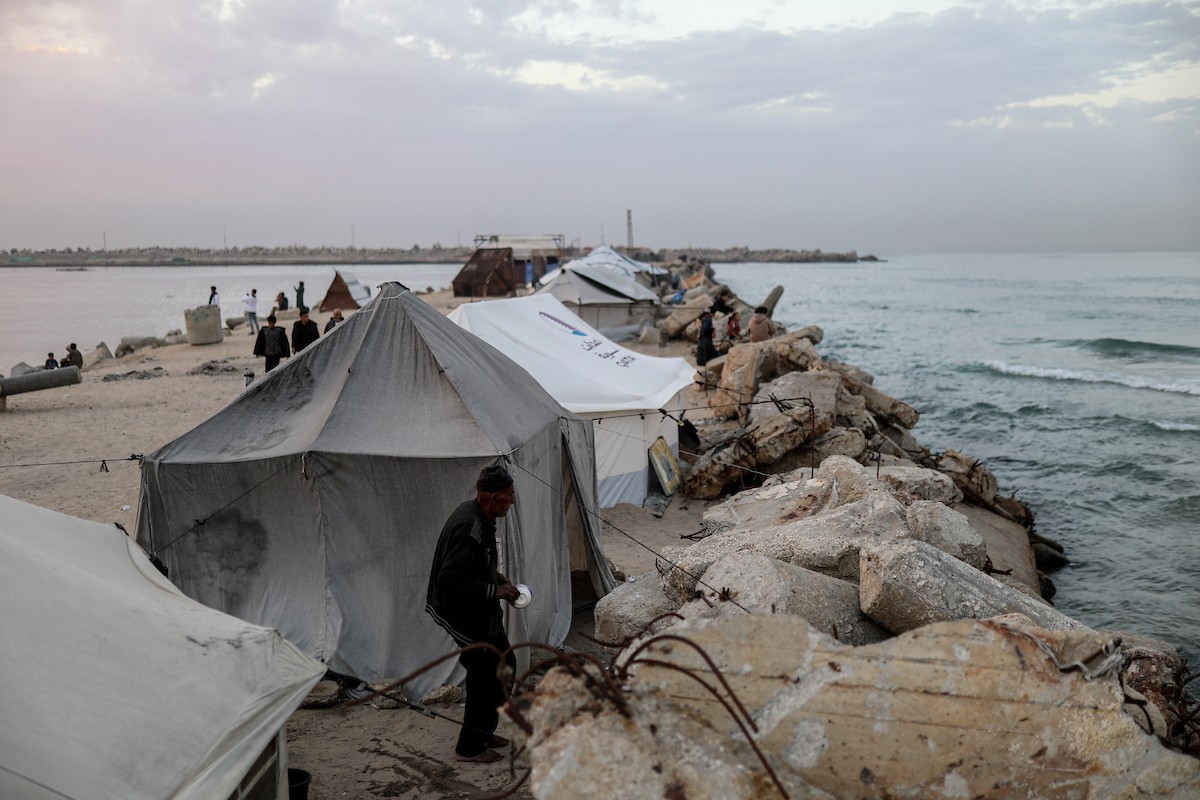 يقضي فلسطينيون نازحون وقتًا على الشاطئ مقابل خيامهم الممتدة على طول ميناء غزة، في غزة، 5 ديسمبر/كانون الأول 2025. تصوير: عمر أشتوي