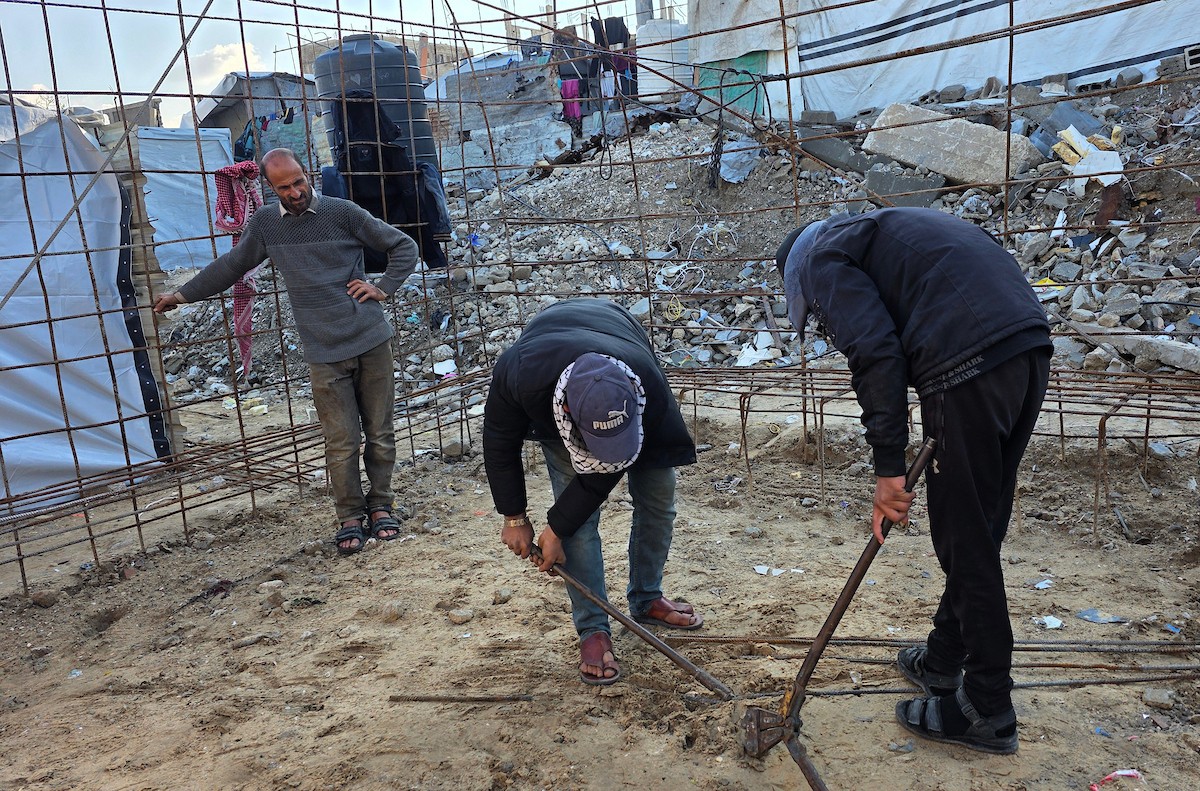 الفلسطيني هشام أبو عية يبني مأوى مؤقت لعائلته المكونة من ثمانية أفراد باستخدام قضبان حديدية استخرجها من أنقاض منزله الذي دُمر في هجمات إسرائيلية بمنطقة بطن السمين في خان يونس،  19 ديسمبر/كانون الأول 2025. تصوير: طارق محمد/ (APA )