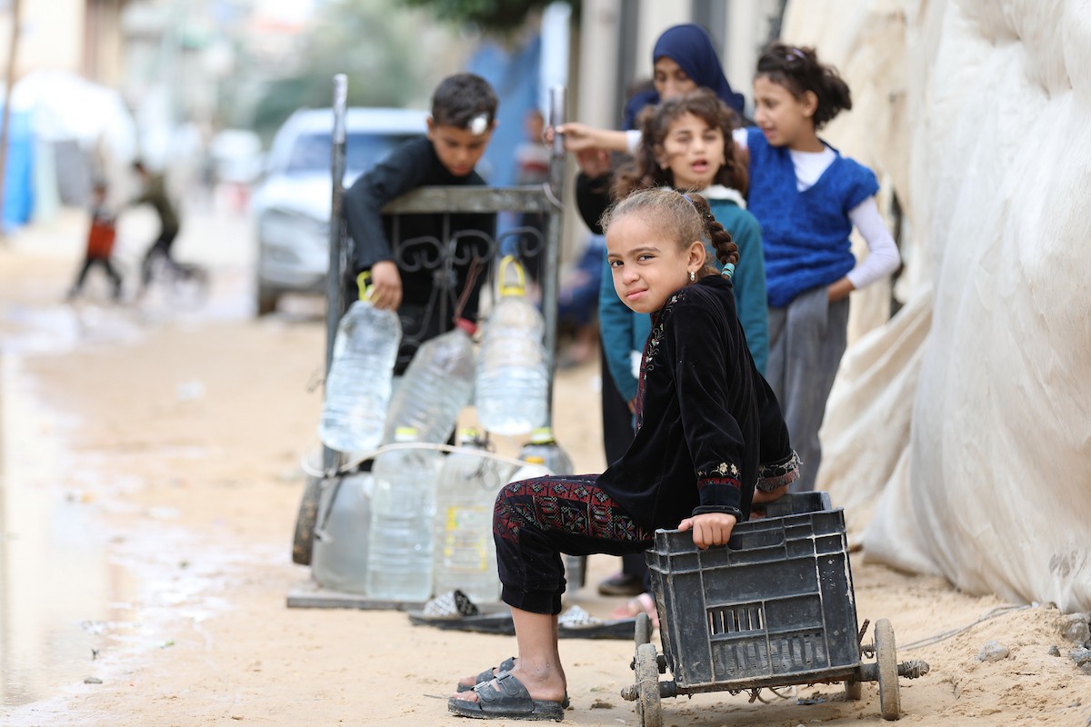 يتجمع الفلسطينيون لتلقي مياه الشرب مجانًا في مخيم البريج للاجئين، في ظل تفاقم أزمة نقص المياه وتدهور البنية التحتية، 21 ديسمبر/كانون الأول 2025. صورة: رمزي أبو عامر