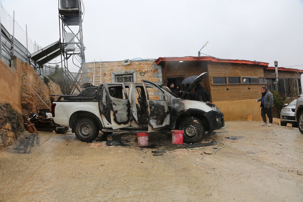 فلسطينيون يقفون في موقع حريق سيارة أشعله مستوطنون إسرائيليون في بلدة حوارة، جنوب نابلس في الضفة الغربية، 28 ديسمبر/كانون الأول 2025. صورة: محمد ناصر