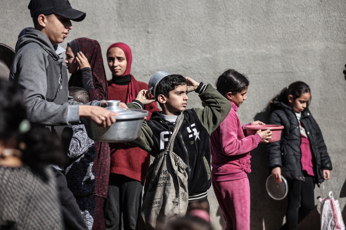 يتلقى فلسطينيون في مخيم النصيرات وسط قطاع غزة وجبات ساخنة من جمعية خيرية تُعنى بالنازحين جراء الهجمات الإسرائيلية، بينما يتجمع حشد كبير، يضم نساءً وأطفالاً، خلال عملية التوزيع، في 30 ديسمبر/كانون الأول 2025. صورة: معز صالحي