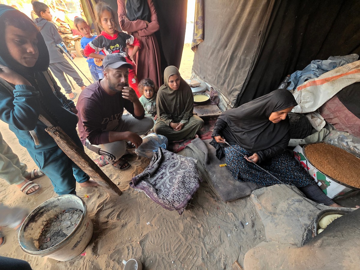 يتجمع فلسطينيون حول أفران طينية مؤقتة لطهي الطعام في قطاع غزة، بعد عشرة أسابيع من وقف إطلاق النار، في ظل شحّ غاز الطهي بسبب القيود الإسرائيلية على دخوله إلى القطاع