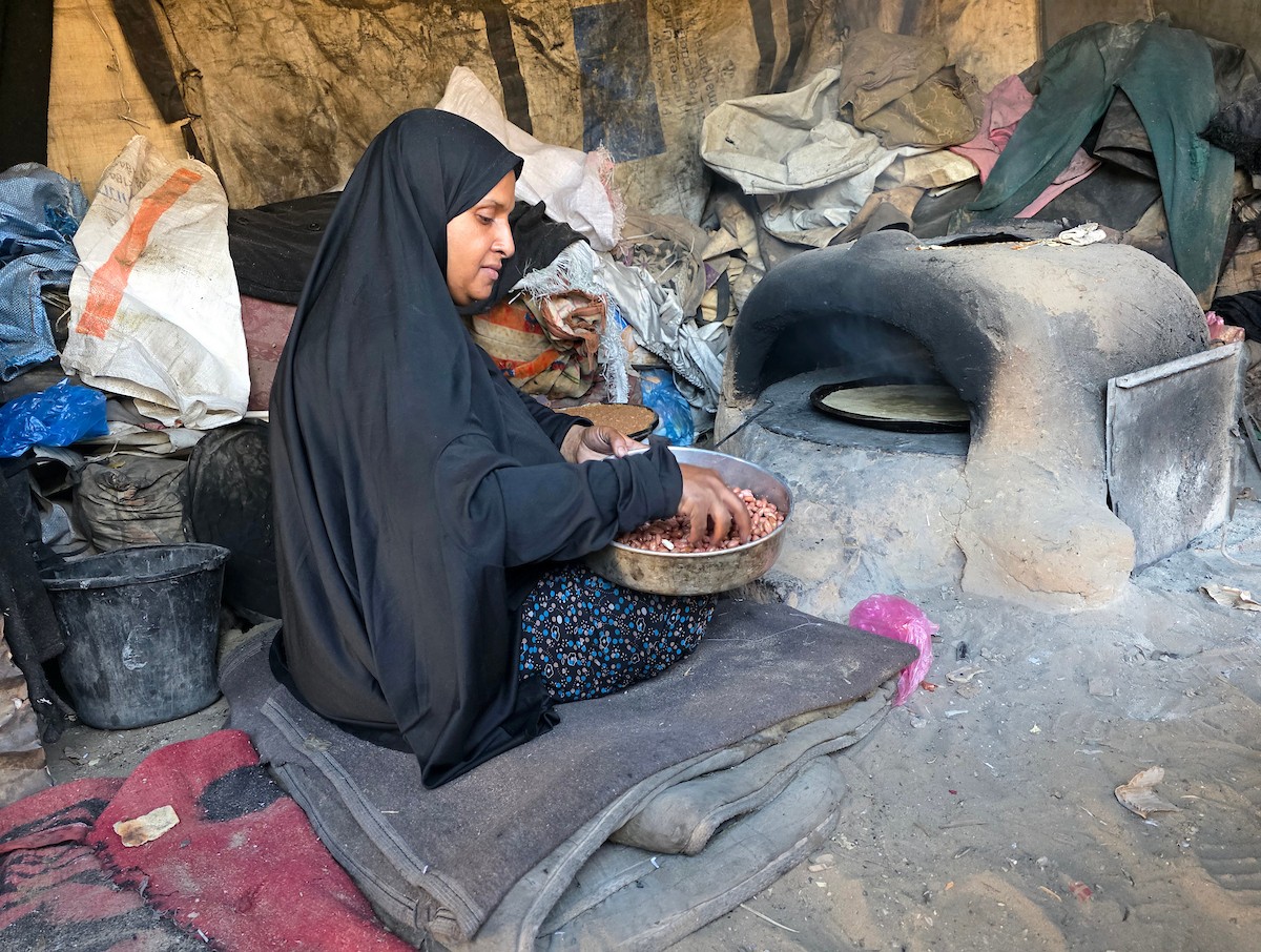 يتجمع فلسطينيون حول أفران طينية مؤقتة لطهي الطعام في قطاع غزة، بعد عشرة أسابيع من وقف إطلاق النار، في ظل شحّ غاز الطهي بسبب القيود الإسرائيلية على دخوله إلى القطاع