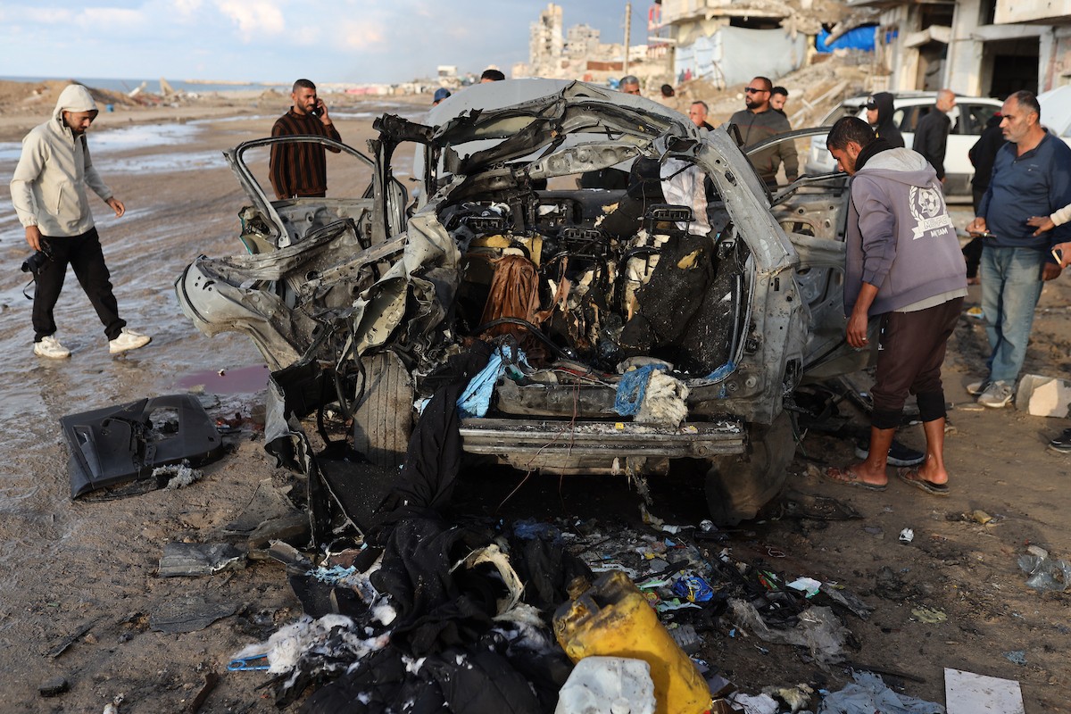 فلسطينيون يتفقدون موقع غارة إسرائيلية استهدفت سيارة على شارع لرشيد غرب مدينة غزة، 13 ديسمبر/كانون الأول 2025. صور: عمر أشتوي