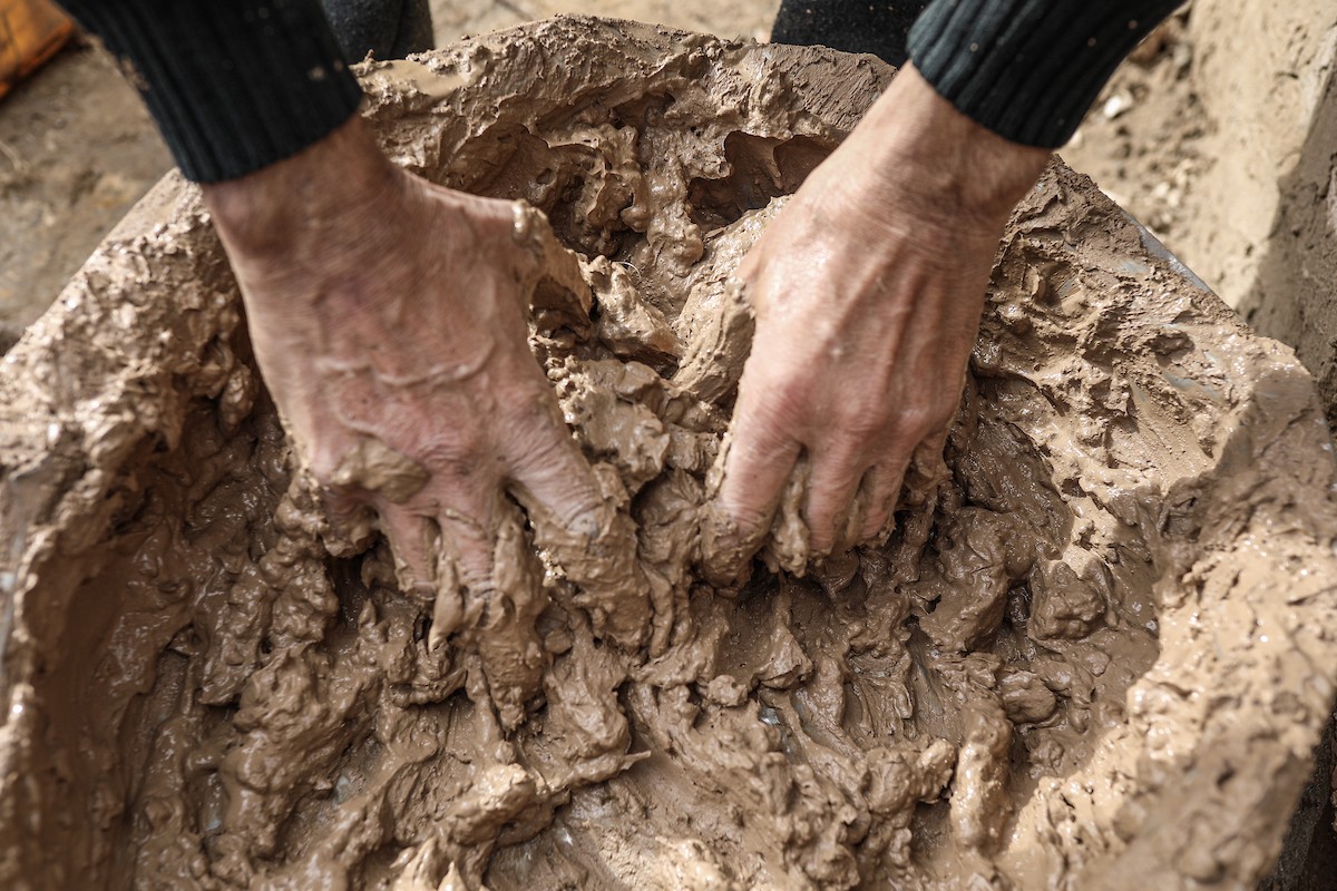 الفلسطيني أحمد المبحوح، مريض سرطان، يبني منزلاً طينياً بيديه في مخيم البريج للاجئين وسط قطاع غزة، 15 ديسمبر/كانون الأول 2025. عدسة: رمزي أبو عامر