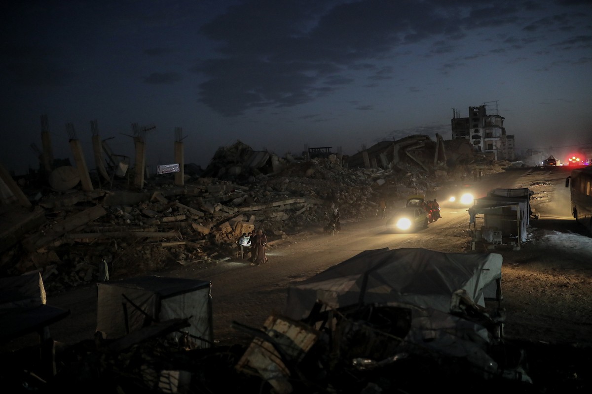 يعيش الفلسطينيون حياتهم اليومية ليلاً في خيام نصبت فوق أنقاض المباني المدمرة في حي الشيخ رضوان وسط مدينة غزة، 5 ديسمبر/كانون الأول 2025.تصوير: عمر أشتوي