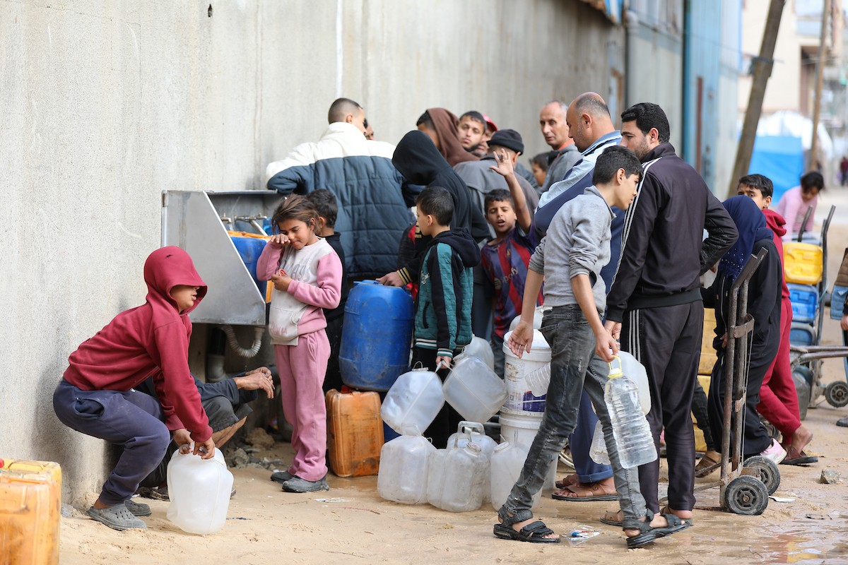 يتجمع الفلسطينيون لتلقي مياه الشرب مجانًا في مخيم البريج للاجئين، في ظل تفاقم أزمة نقص المياه وتدهور البنية التحتية، 21 ديسمبر/كانون الأول 2025. صورة: رمزي أبو عامر