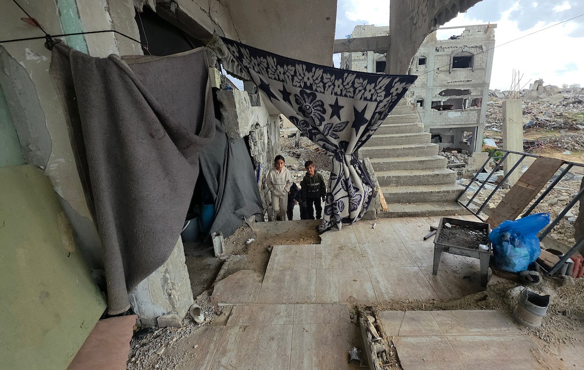 عائلة فلسطينية تحتمي من برد الشتاء القارس في خيمة نصبتها فوق منزلها المدمر قرب الخط الأصفر في خان يونس، جنوب قطاع غزة، ١٧ ديسمبر/كانون الأول ٢٠٢٥. تصوير: طارق محمد/وكالة الأنباء الفلسطينية (APA )