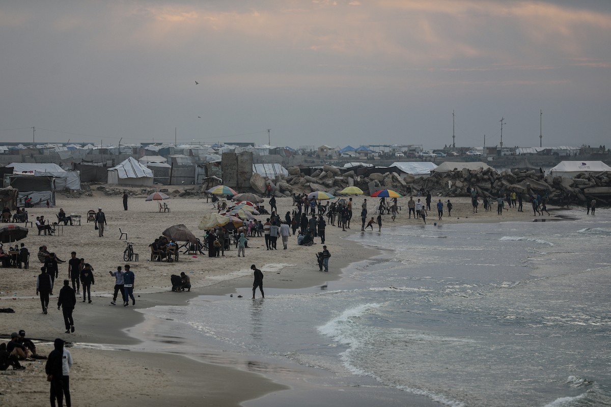 يقضي فلسطينيون نازحون وقتًا على الشاطئ مقابل خيامهم الممتدة على طول ميناء غزة، في غزة، 5 ديسمبر/كانون الأول 2025. تصوير: عمر أشتوي