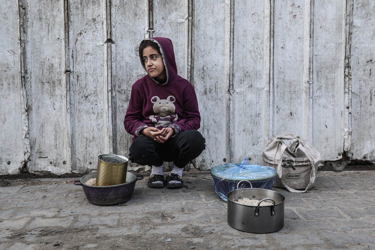 يتلقى فلسطينيون في مخيم النصيرات وسط قطاع غزة وجبات ساخنة من جمعية خيرية تُعنى بالنازحين جراء الهجمات الإسرائيلية، بينما يتجمع حشد كبير، يضم نساءً وأطفالاً، خلال عملية التوزيع، في 30 ديسمبر/كانون الأول 2025. صورة: معز صالحي