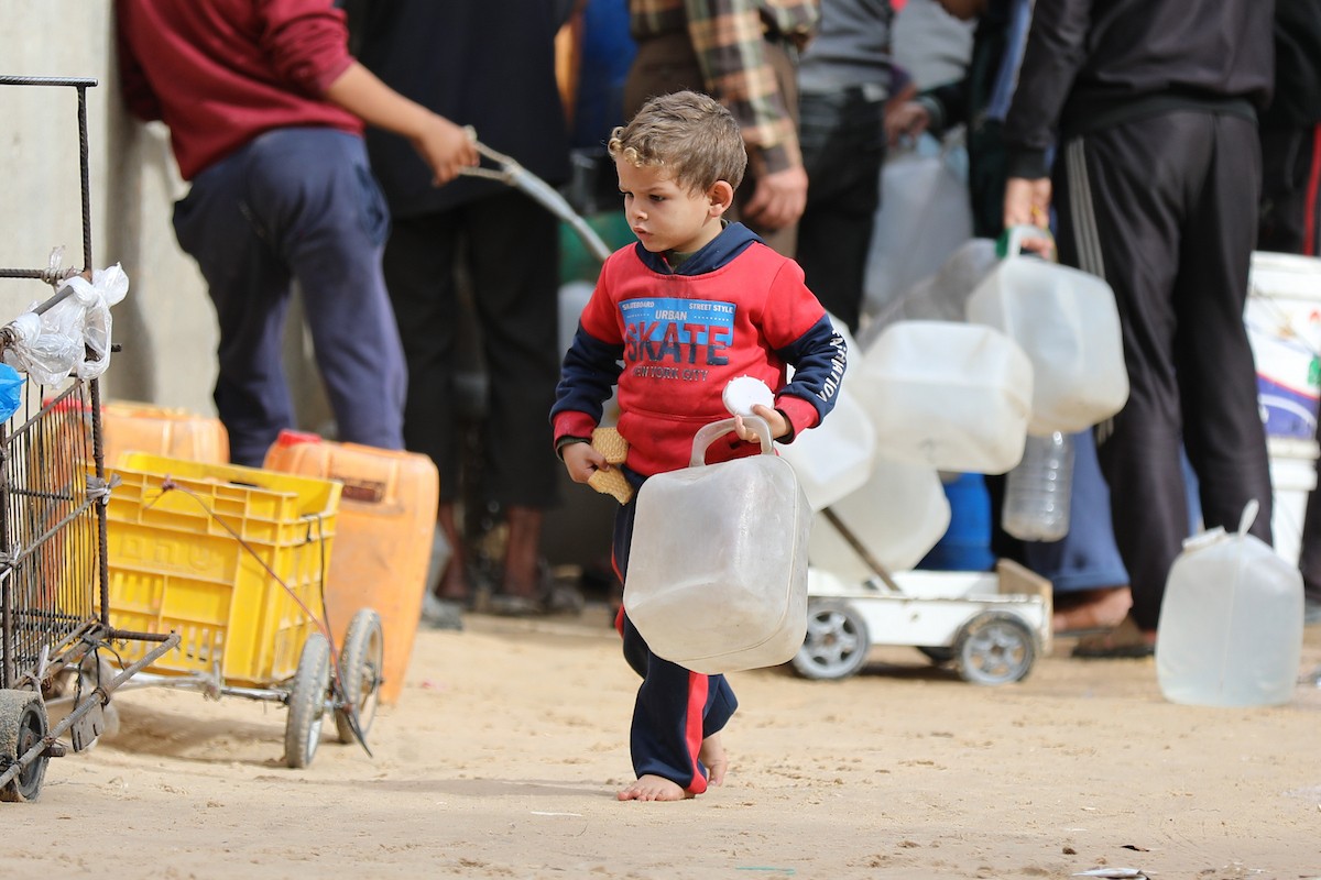 يتجمع الفلسطينيون لتلقي مياه الشرب مجانًا في مخيم البريج للاجئين، في ظل تفاقم أزمة نقص المياه وتدهور البنية التحتية، 21 ديسمبر/كانون الأول 2025. صورة: رمزي أبو عامر