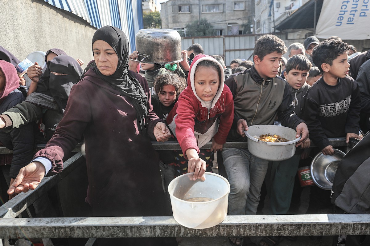 يتلقى فلسطينيون في مخيم النصيرات وسط قطاع غزة وجبات ساخنة من جمعية خيرية تُعنى بالنازحين جراء الهجمات الإسرائيلية، بينما يتجمع حشد كبير، يضم نساءً وأطفالاً، خلال عملية التوزيع، في 30 ديسمبر/كانون الأول 2025. صورة: معز صالحي