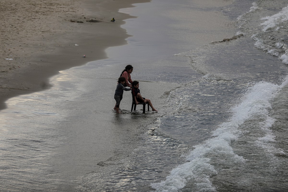 يقضي فلسطينيون نازحون وقتًا على الشاطئ مقابل خيامهم الممتدة على طول ميناء غزة، في غزة، 5 ديسمبر/كانون الأول 2025. تصوير: عمر أشتوي