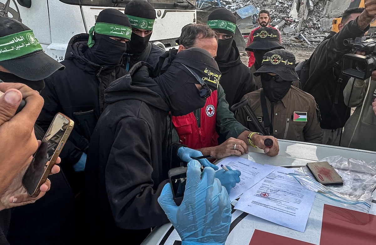 مسلحون من حماس والجهاد الإسلامي في فلسطين يسلمون لأفراد الصليب الأحمر جثة استعادوها من بيت لاهيا قبل تسليمها لإسرائيل لتحديد ما إذا كانت تعود لأحد الرهائن، شمال قطاع غزة، 3 ديسمبر/كانون الأول 2025