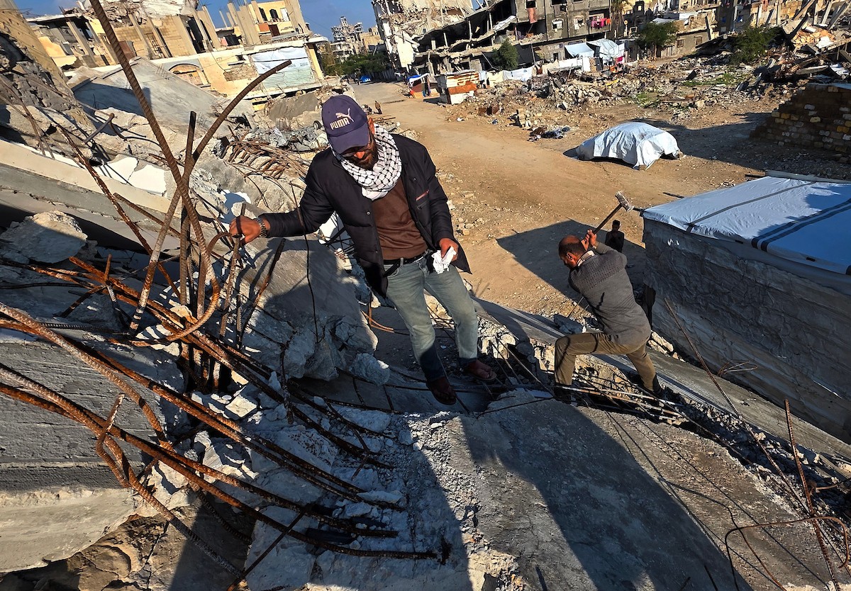 الفلسطيني هشام أبو عية يبني مأوى مؤقت لعائلته المكونة من ثمانية أفراد باستخدام قضبان حديدية استخرجها من أنقاض منزله الذي دُمر في هجمات إسرائيلية بمنطقة بطن السمين في خان يونس،  19 ديسمبر/كانون الأول 2025. تصوير: طارق محمد/ (APA )