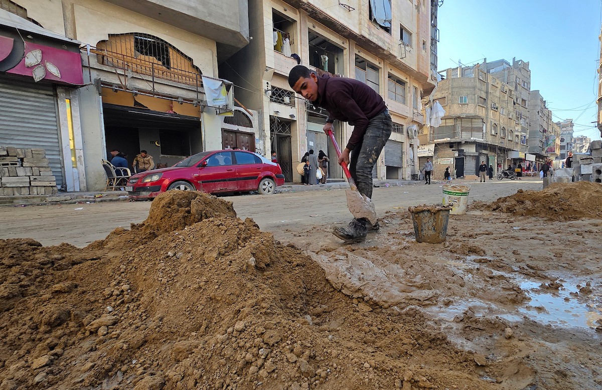 في خان يونس، جنوب قطاع غزة، يقوم أصحاب المتاجر الفلسطينيون بإزالة الأنقاض بأيديهم، ويعيدون بناء متاجرهم المتضررة باستخدام الحجارة والطين الأحمر، 27 ديسمبر/كانون الأول 2025 (صورة: طارق محمد)