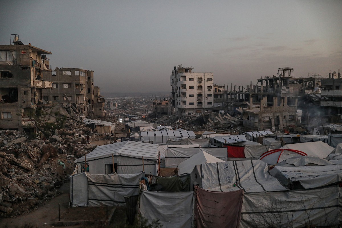 يعيش الفلسطينيون حياتهم اليومية ليلاً في خيام نصبت فوق أنقاض المباني المدمرة في حي الشيخ رضوان وسط مدينة غزة، 5 ديسمبر/كانون الأول 2025.تصوير: عمر أشتوي