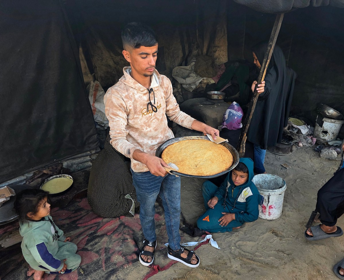 يتجمع فلسطينيون حول أفران طينية مؤقتة لطهي الطعام في قطاع غزة، بعد عشرة أسابيع من وقف إطلاق النار، في ظل شحّ غاز الطهي بسبب القيود الإسرائيلية على دخوله إلى القطاع