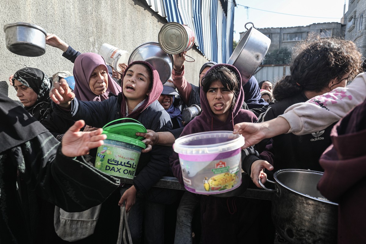 يتلقى فلسطينيون في مخيم النصيرات وسط قطاع غزة وجبات ساخنة من جمعية خيرية تُعنى بالنازحين جراء الهجمات الإسرائيلية، بينما يتجمع حشد كبير، يضم نساءً وأطفالاً، خلال عملية التوزيع، في 30 ديسمبر/كانون الأول 2025. صورة: معز صالحي