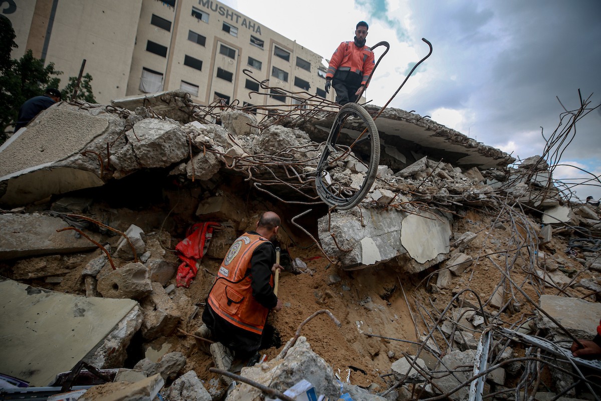 عمال الدفاع المدني الفلسطيني يبحثون عن جثث في مبنى منهار يعود لعائلة سالم، استُهدف بغارات إسرائيلية في بداية الحرب، في شارع الجلاء بمدينة غزة، يوم الاثنين 15 ديسمبر/كانون الأول 2025. صورة: عمر أشتوي