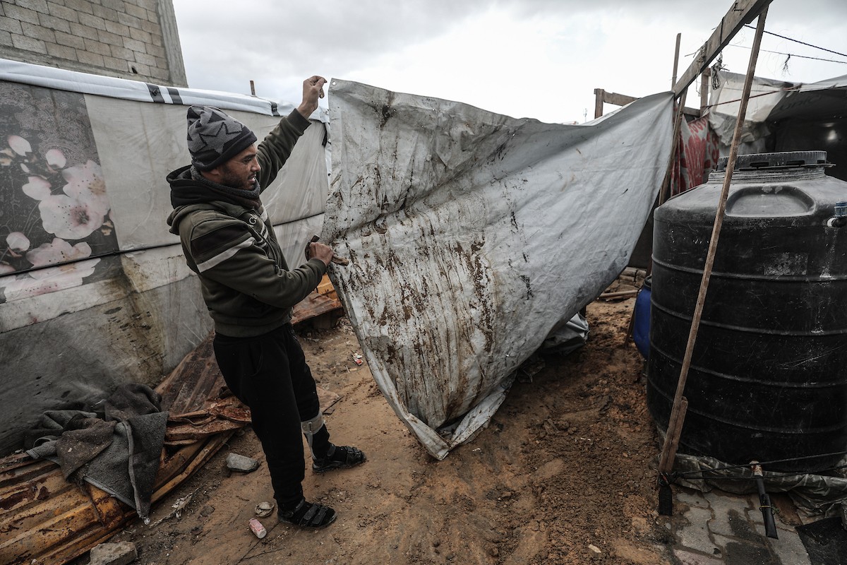 أحمد أبو ليلى أب لخمسة أطفال أصيب في الحرب  يحاول إصلاح خيمته بعد أن تضررت جراء الأمطار الغزيرة والرياح العاتية التي اجتاحت مخيم النصيرات وسط قطاع غزة، 28 ديسمبر/كانون الأول 2025.تصوير: معز صالحي