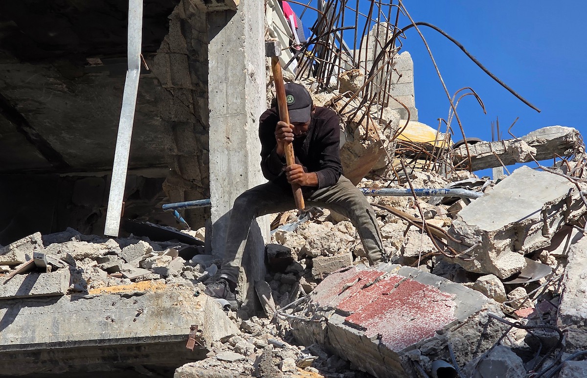 في خان يونس، جنوب قطاع غزة، يقوم أصحاب المتاجر الفلسطينيون بإزالة الأنقاض بأيديهم، ويعيدون بناء متاجرهم المتضررة باستخدام الحجارة والطين الأحمر، 27 ديسمبر/كانون الأول 2025 (صورة: طارق محمد)