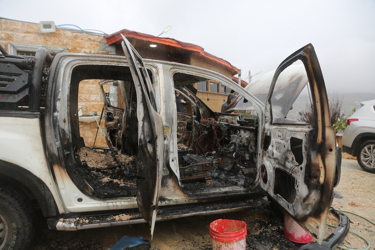 فلسطينيون يقفون في موقع حريق سيارة أشعله مستوطنون إسرائيليون في بلدة حوارة، جنوب نابلس في الضفة الغربية، 28 ديسمبر/كانون الأول 2025. صورة: محمد ناصر