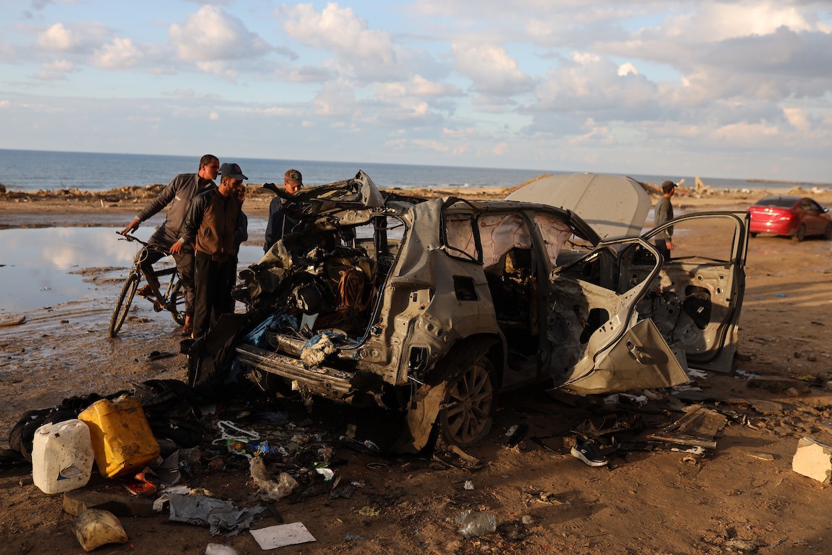 فلسطينيون يتفقدون موقع غارة إسرائيلية استهدفت سيارة على شارع لرشيد غرب مدينة غزة، 13 ديسمبر/كانون الأول 2025. صور: عمر أشتوي