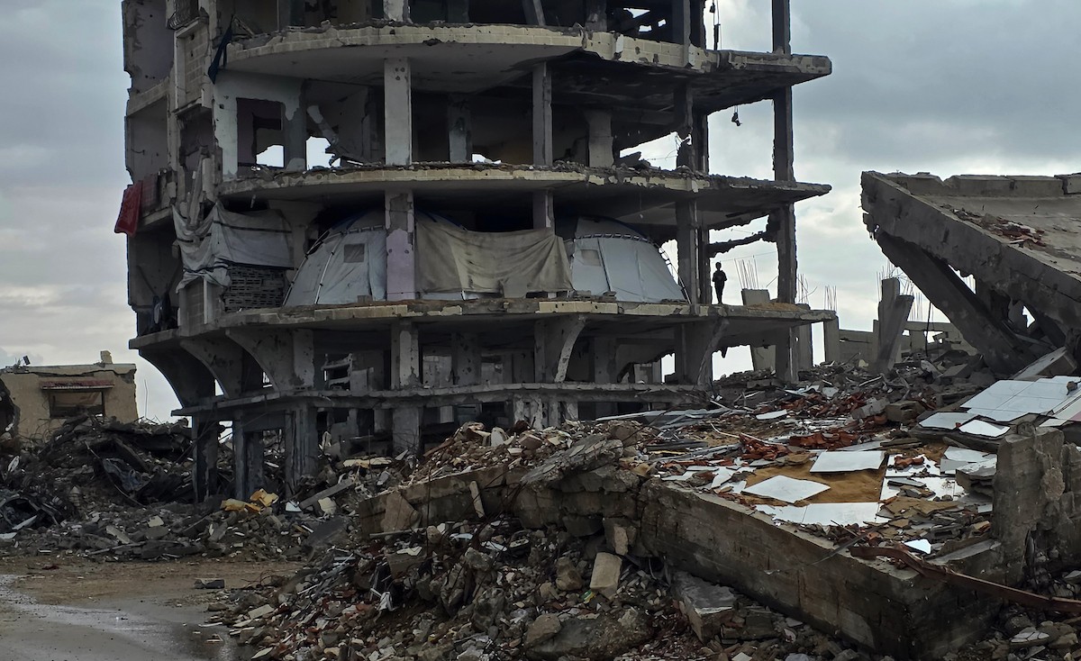 عائلة فلسطينية تحتمي من برد الشتاء القارس في خيمة نصبتها فوق منزلها المدمر قرب الخط الأصفر في خان يونس، جنوب قطاع غزة، ١٧ ديسمبر/كانون الأول ٢٠٢٥. تصوير: طارق محمد/وكالة الأنباء الفلسطينية (APA )