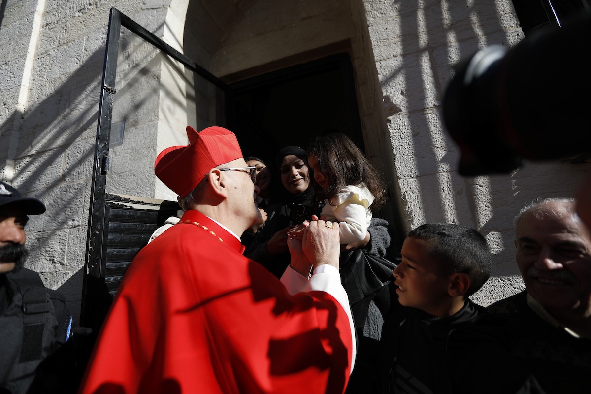 البطريرك اللاتيني للقدس، الكاردينال الإيطالي بييرباتيستا بيتسابالا يستقبل الحجاج والسياح لدى وصوله لترؤس قداس منتصف الليل في كنيسة المهد بمدينة بيت لحم، 24 ديسمبر/كانون الأول 2025،  (صور: مأمون وزواز/ apa)