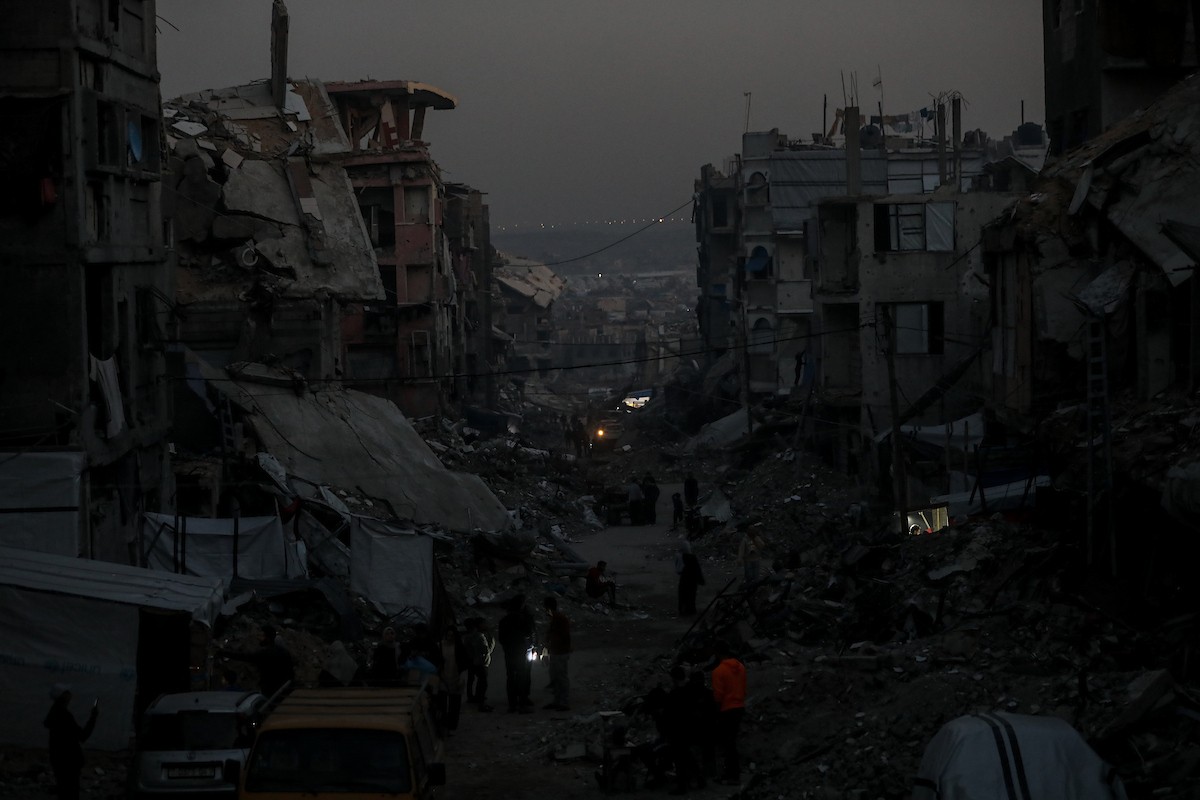 يعيش الفلسطينيون حياتهم اليومية ليلاً في خيام نصبت فوق أنقاض المباني المدمرة في حي الشيخ رضوان وسط مدينة غزة، 5 ديسمبر/كانون الأول 2025.تصوير: عمر أشتوي