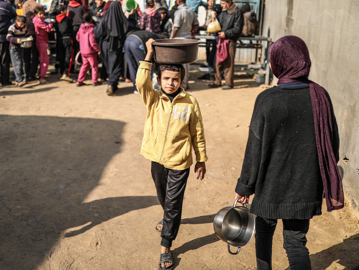 يصطفّ فلسطينيون لتلقّي الطعام من مطبخ خيري في تجمع للنازحين بمخيم النصيرات للاجئين، وسط قطاع غزة. ١٧ ديسمبر/كانون الأول ٢٠٢٥. تصوير: رمزي أبو عامر / (apa)