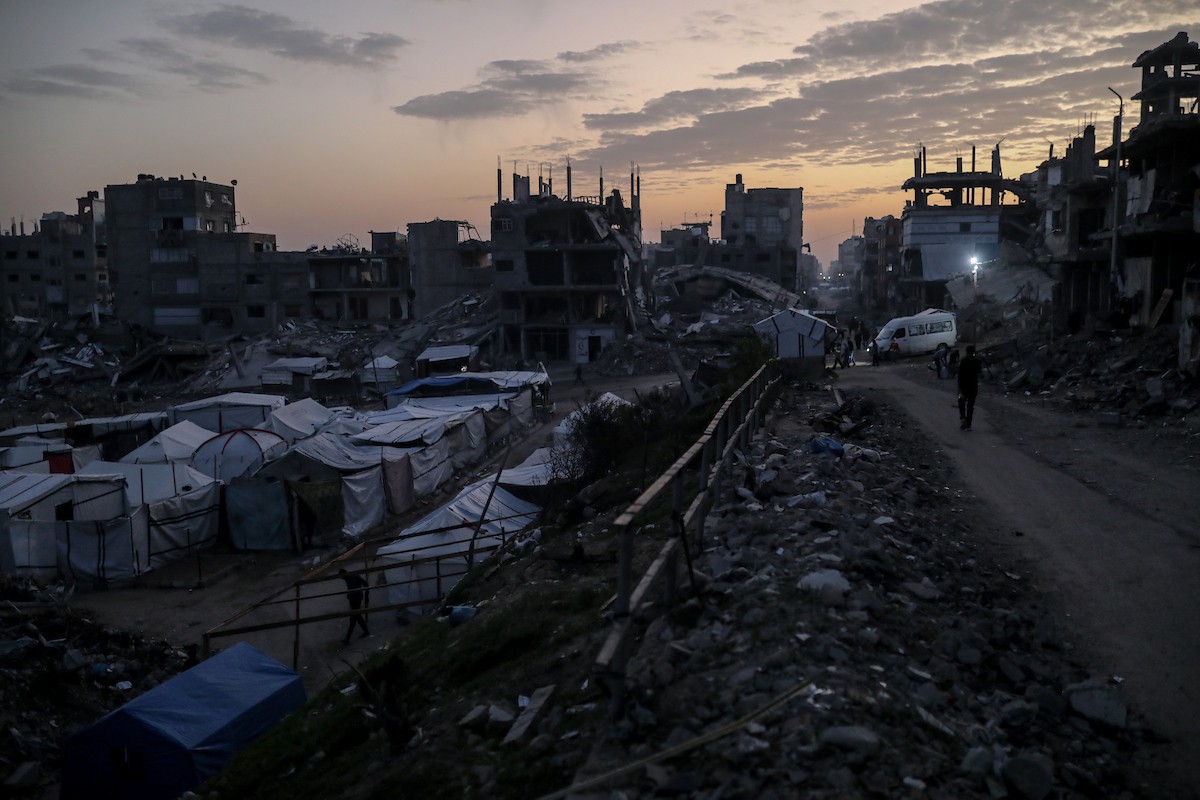 يعيش الفلسطينيون حياتهم اليومية ليلاً في خيام نصبت فوق أنقاض المباني المدمرة في حي الشيخ رضوان وسط مدينة غزة، 5 ديسمبر/كانون الأول 2025.تصوير: عمر أشتوي