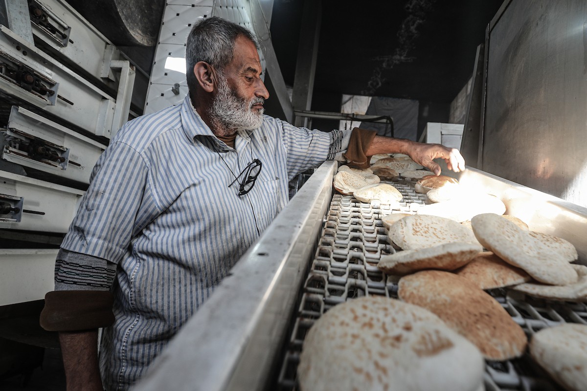 عمال فلسطينيون يعيدون تشغيل أحد أقدم المخابز في مخيم النصيرات للاجئين بعد إغلاقه لمدة عامين بسبب الحرب (22).jpg