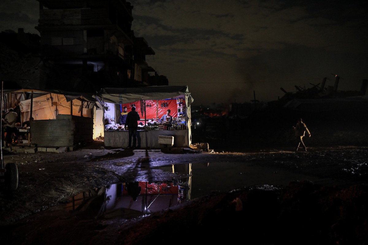 يعيش الفلسطينيون حياتهم اليومية ليلاً في خيام نصبت فوق أنقاض المباني المدمرة في حي الشيخ رضوان وسط مدينة غزة، 5 ديسمبر/كانون الأول 2025.تصوير: عمر أشتوي