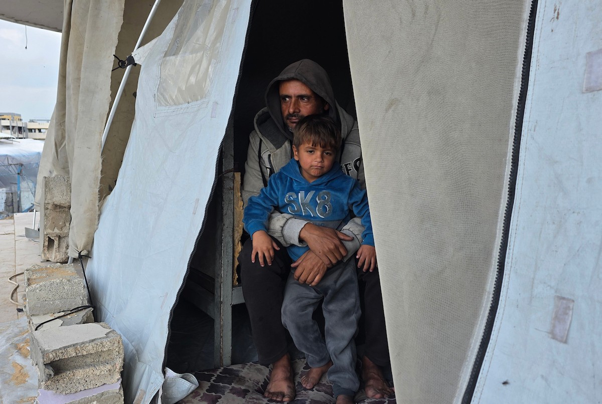 عائلة فلسطينية تحتمي من برد الشتاء القارس في خيمة نصبتها فوق منزلها المدمر قرب الخط الأصفر في خان يونس، جنوب قطاع غزة، ١٧ ديسمبر/كانون الأول ٢٠٢٥. تصوير: طارق محمد/وكالة الأنباء الفلسطينية (APA )