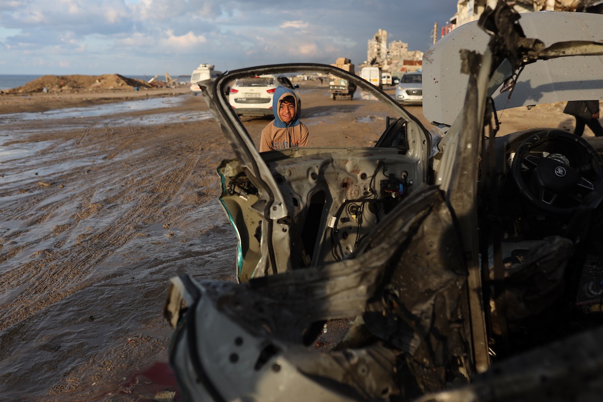 فلسطينيون يتفقدون موقع غارة إسرائيلية استهدفت سيارة على شارع لرشيد غرب مدينة غزة، 13 ديسمبر/كانون الأول 2025. صور: عمر أشتوي