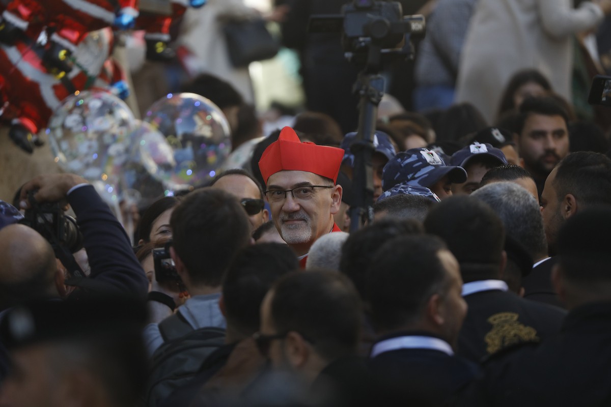 البطريرك اللاتيني للقدس، الكاردينال الإيطالي بييرباتيستا بيتسابالا يستقبل الحجاج والسياح لدى وصوله لترؤس قداس منتصف الليل في كنيسة المهد بمدينة بيت لحم، 24 ديسمبر/كانون الأول 2025،  (صور: مأمون وزواز/ apa)