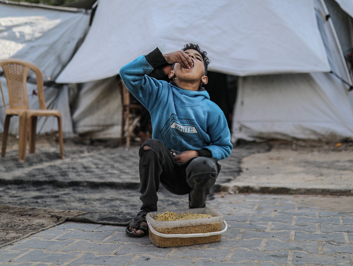 يصطفّ فلسطينيون لتلقّي الطعام من مطبخ خيري في تجمع للنازحين بمخيم النصيرات للاجئين، وسط قطاع غزة. ١٧ ديسمبر/كانون الأول ٢٠٢٥. تصوير: رمزي أبو عامر / (apa)