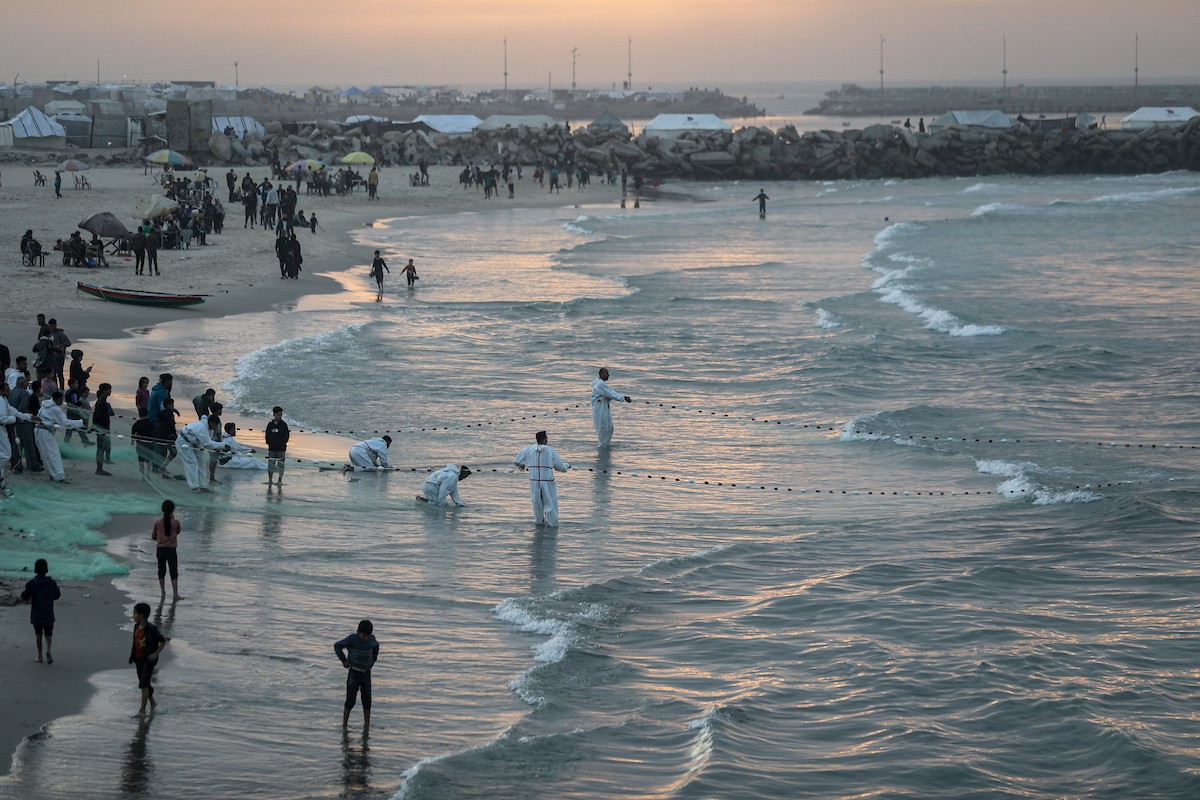 يقضي فلسطينيون نازحون وقتًا على الشاطئ مقابل خيامهم الممتدة على طول ميناء غزة، في غزة، 5 ديسمبر/كانون الأول 2025. تصوير: عمر أشتوي