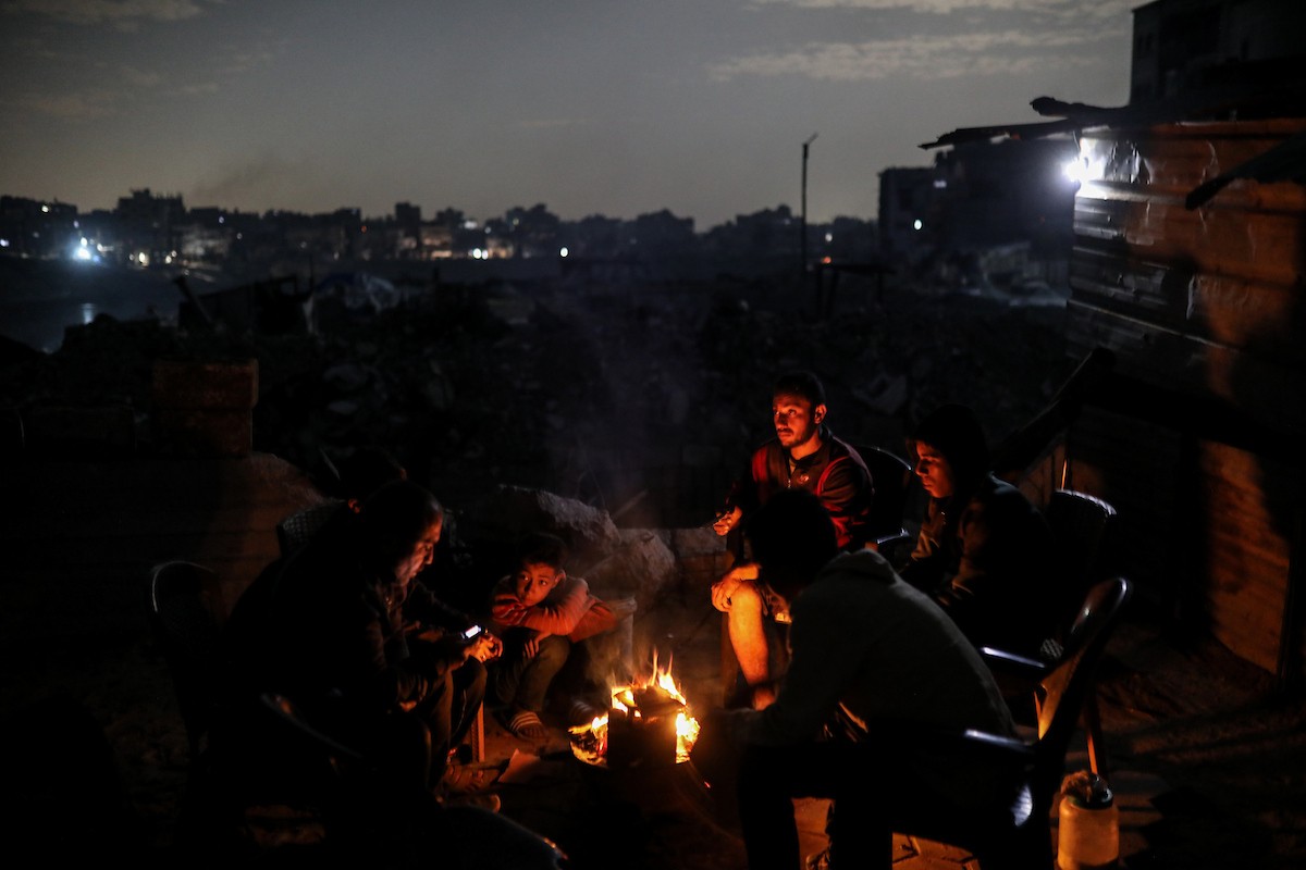 يعيش الفلسطينيون حياتهم اليومية ليلاً في خيام نصبت فوق أنقاض المباني المدمرة في حي الشيخ رضوان وسط مدينة غزة، 5 ديسمبر/كانون الأول 2025.تصوير: عمر أشتوي