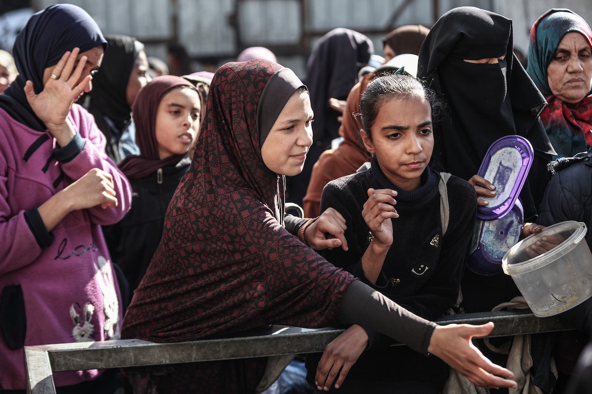 يتلقى فلسطينيون في مخيم النصيرات وسط قطاع غزة وجبات ساخنة من جمعية خيرية تُعنى بالنازحين جراء الهجمات الإسرائيلية، بينما يتجمع حشد كبير، يضم نساءً وأطفالاً، خلال عملية التوزيع، في 30 ديسمبر/كانون الأول 2025. صورة: معز صالحي