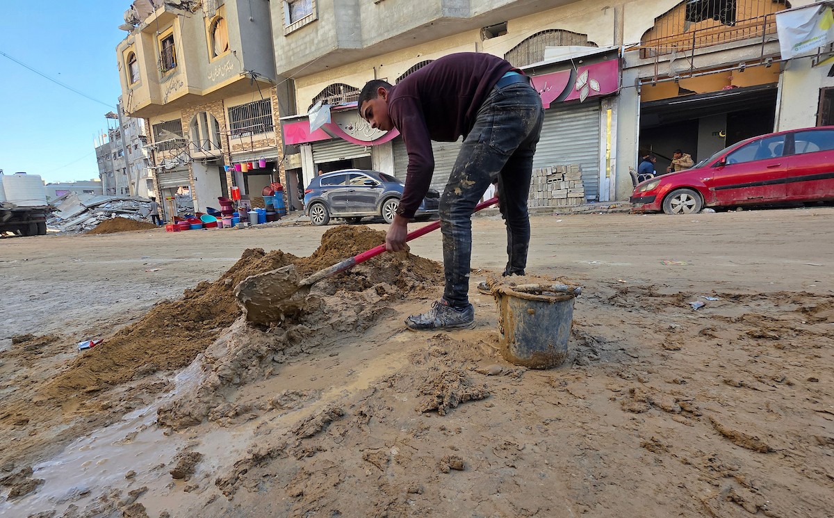 في خان يونس، جنوب قطاع غزة، يقوم أصحاب المتاجر الفلسطينيون بإزالة الأنقاض بأيديهم، ويعيدون بناء متاجرهم المتضررة باستخدام الحجارة والطين الأحمر، 27 ديسمبر/كانون الأول 2025 (صورة: طارق محمد)